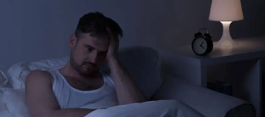 man stressed laying in bed